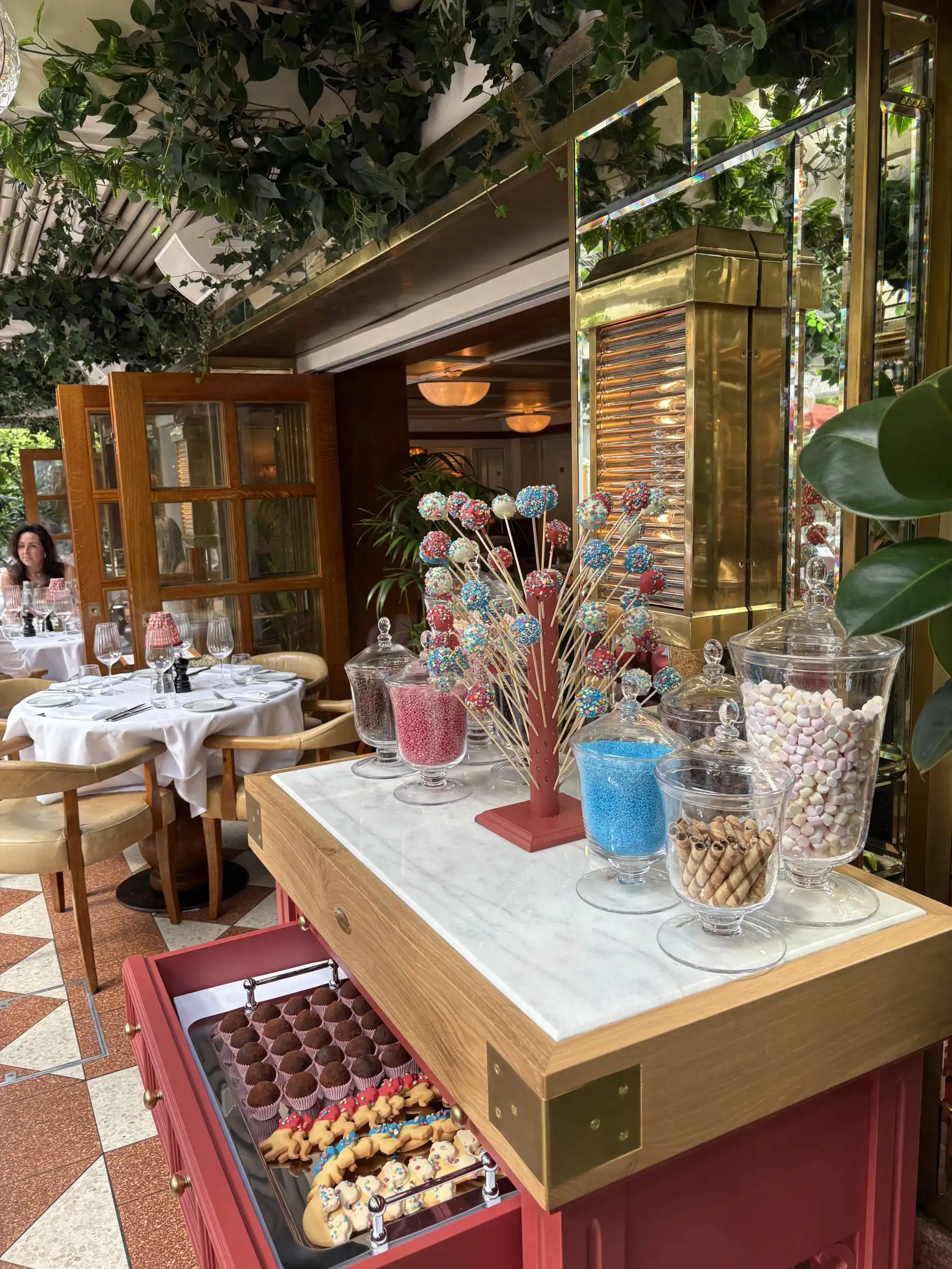 Dessert station with colorful candy skewers, jars of sprinkles, and pastries at an elegant restaurant setting.