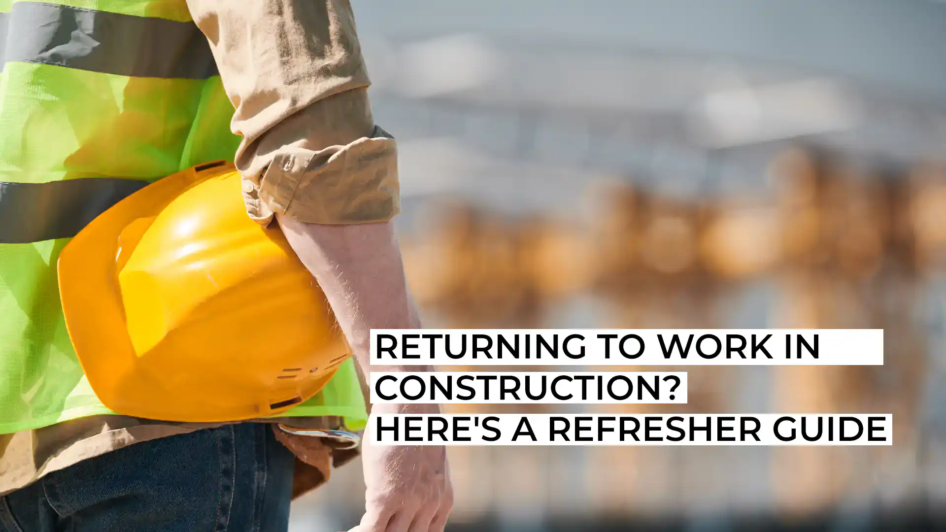 Construction worker holding a yellow helmet on site.