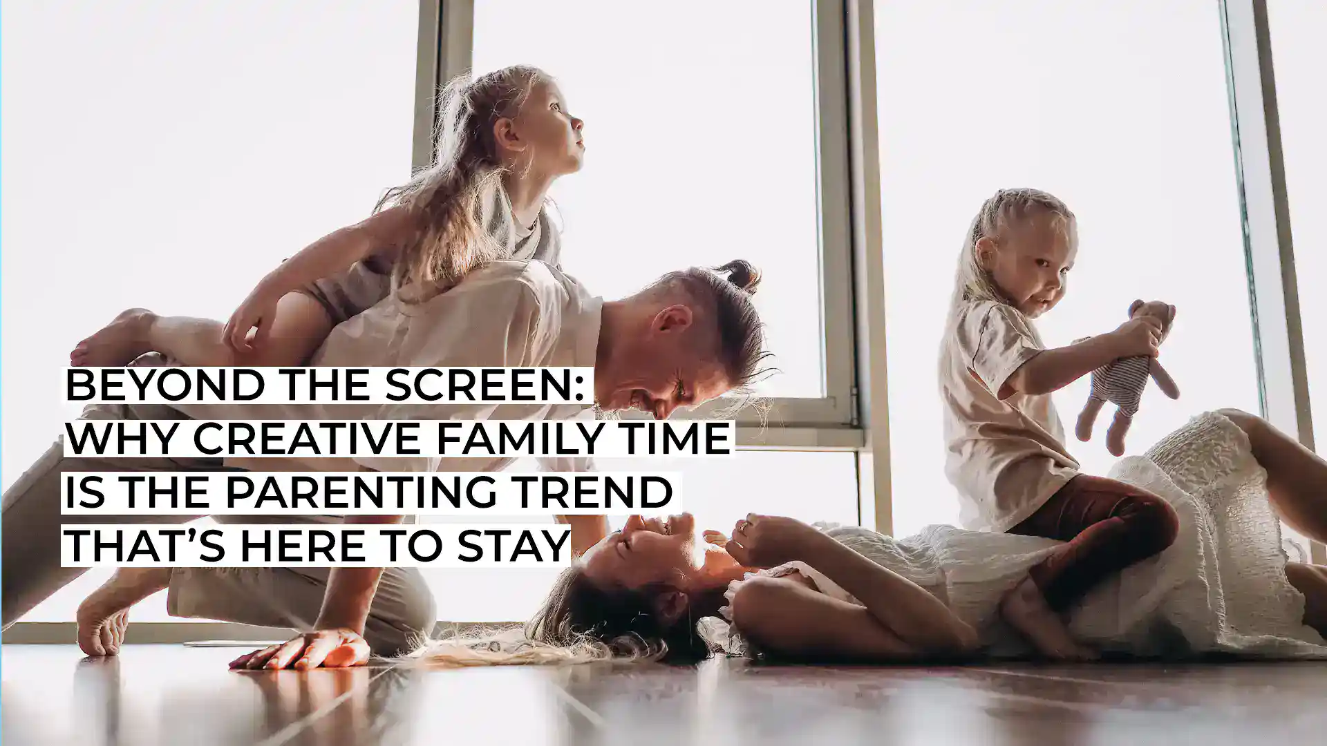 Family playing and relaxing together near large window.