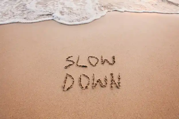 Slow Down text written in sand