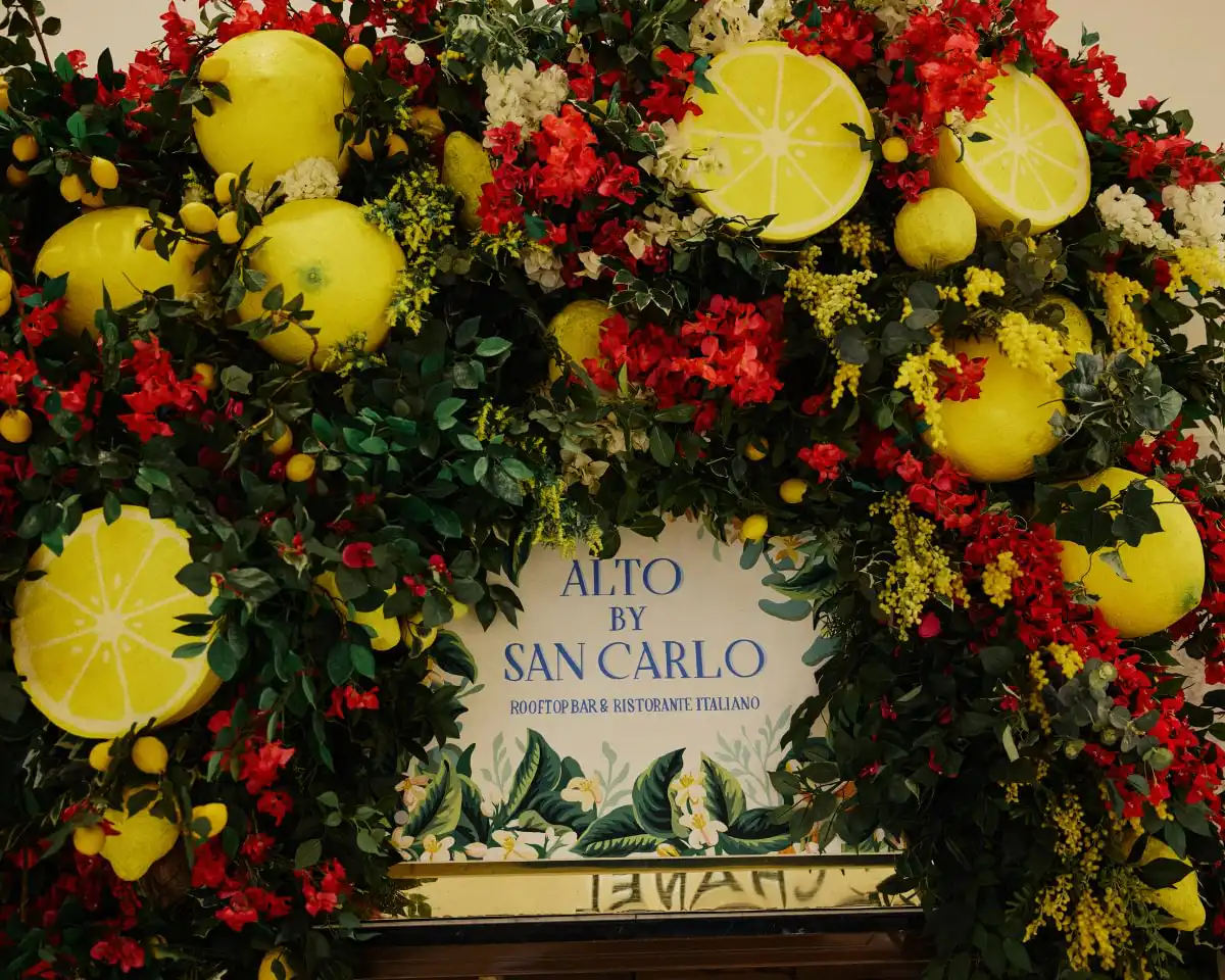 Floral arrangement with large lemons around a sign for Alto by San Carlo rooftop bar and ristorante italiano.