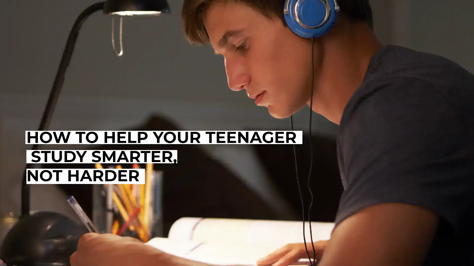 Teenager focused on studying with headphones in a modern setting.