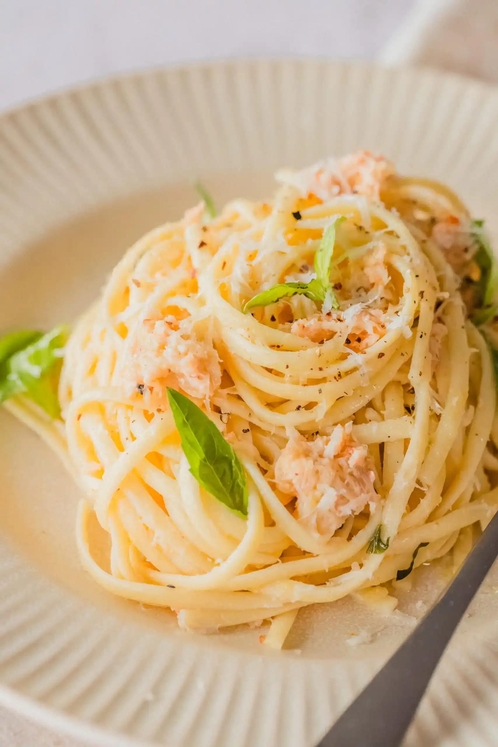 Close-up of creamy salmon pasta with fresh basil on a white plate.