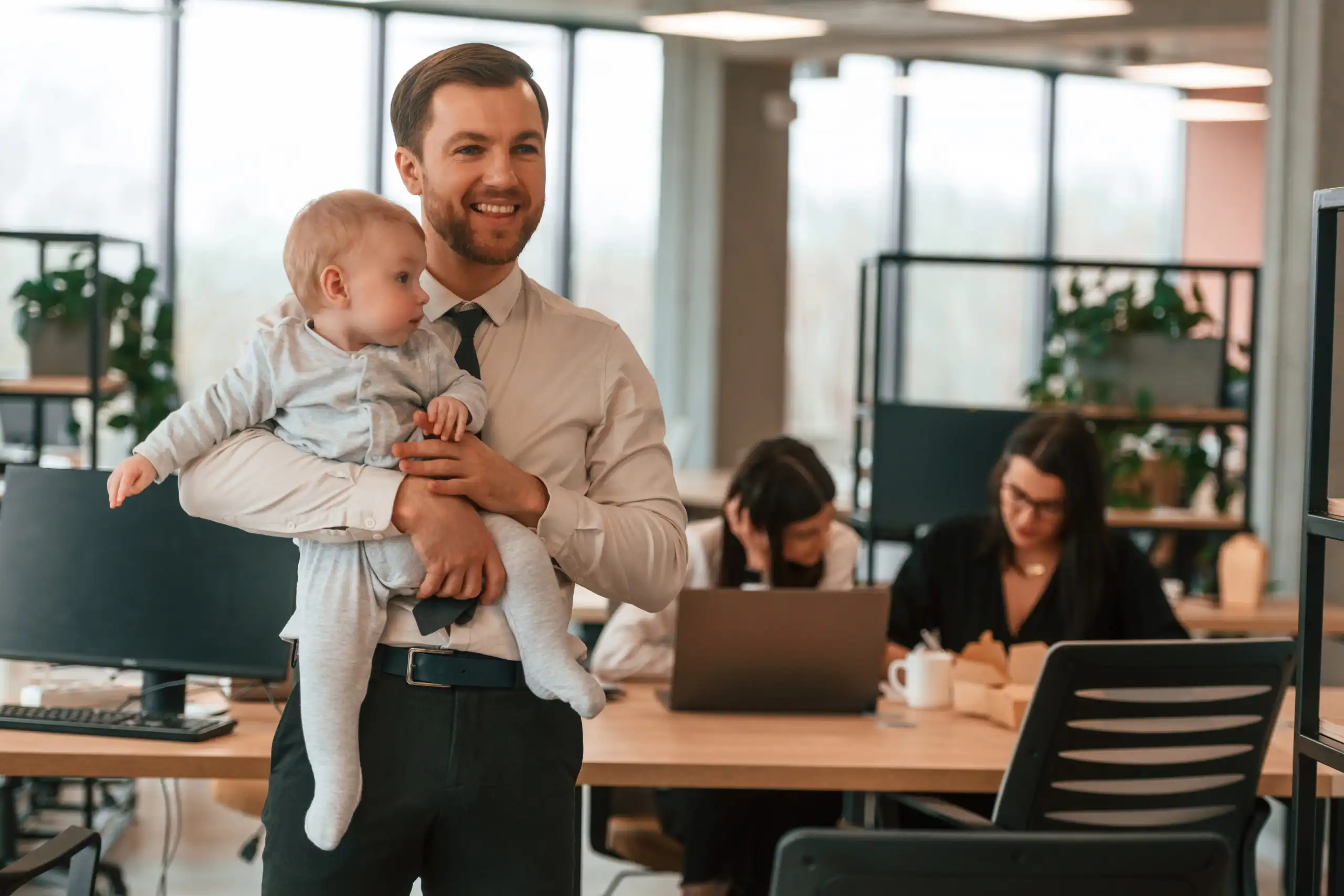 Father holding baby in office workplace setting