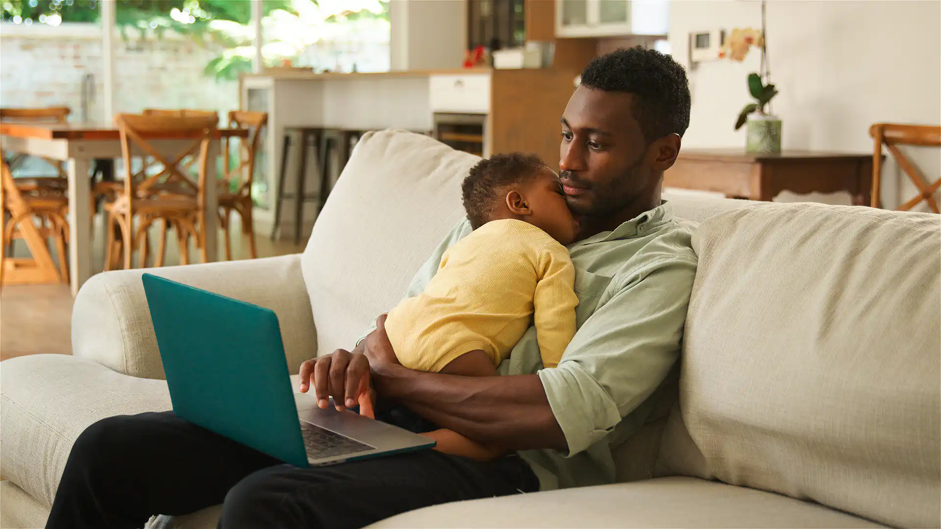New Dad paternity leave legislation. Parent holding baby whilst he works
