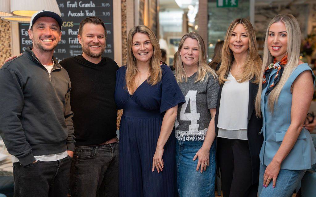 Six smiling members of the BROOD team standing together indoors