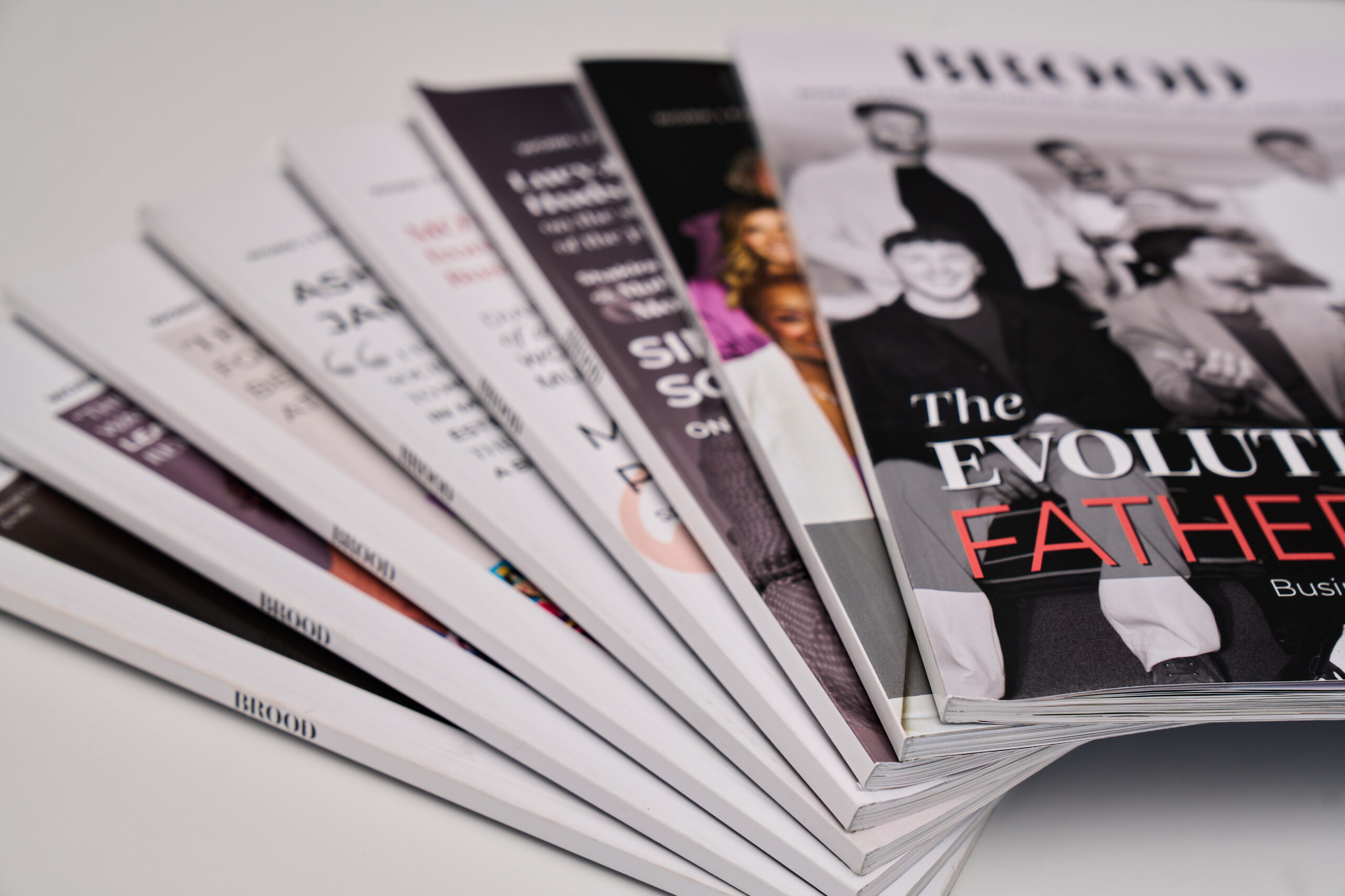 A fanned stack of glossy BROOD Magazine issues on a pale surface