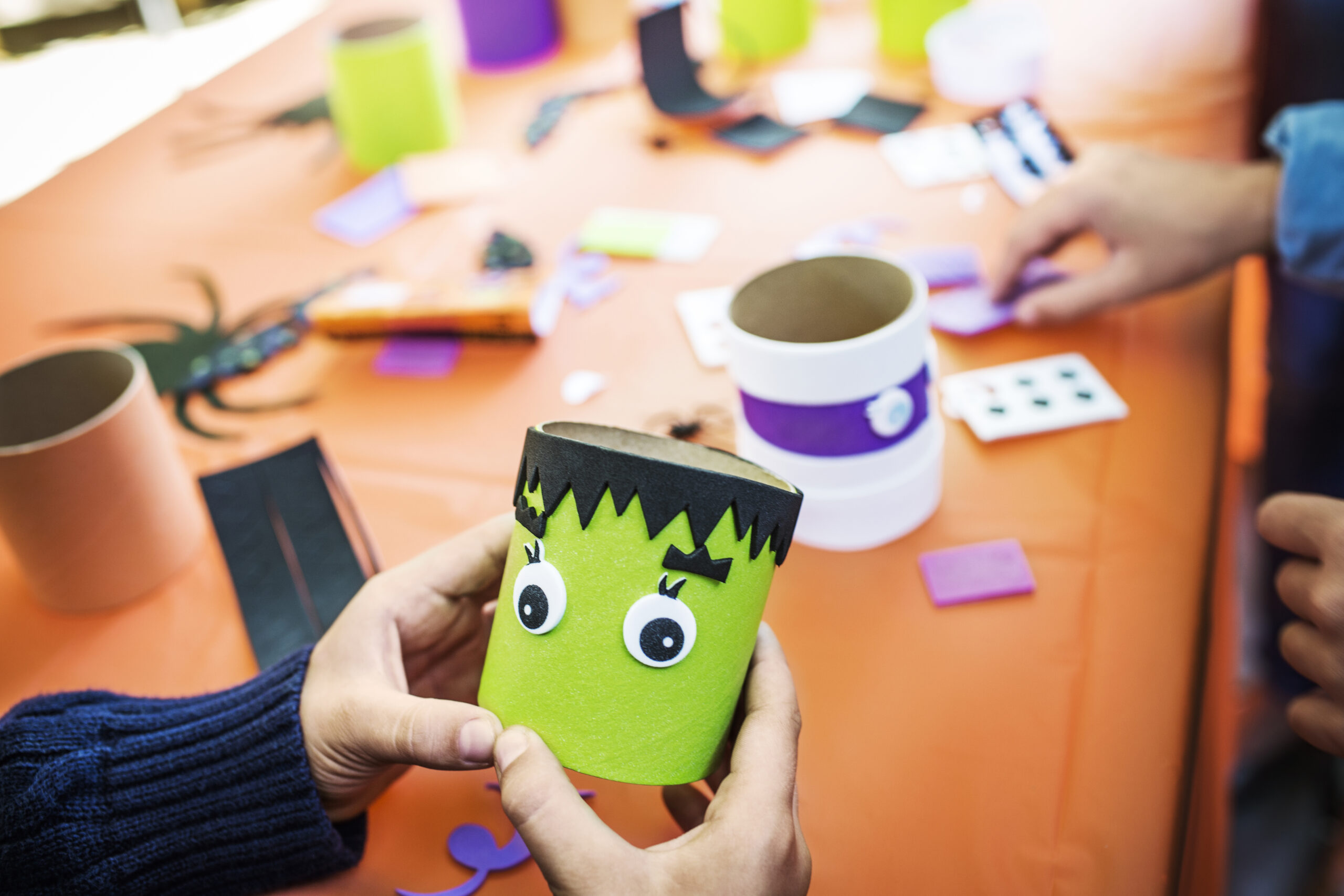 Hands making green Frankenstein craft for Halloween