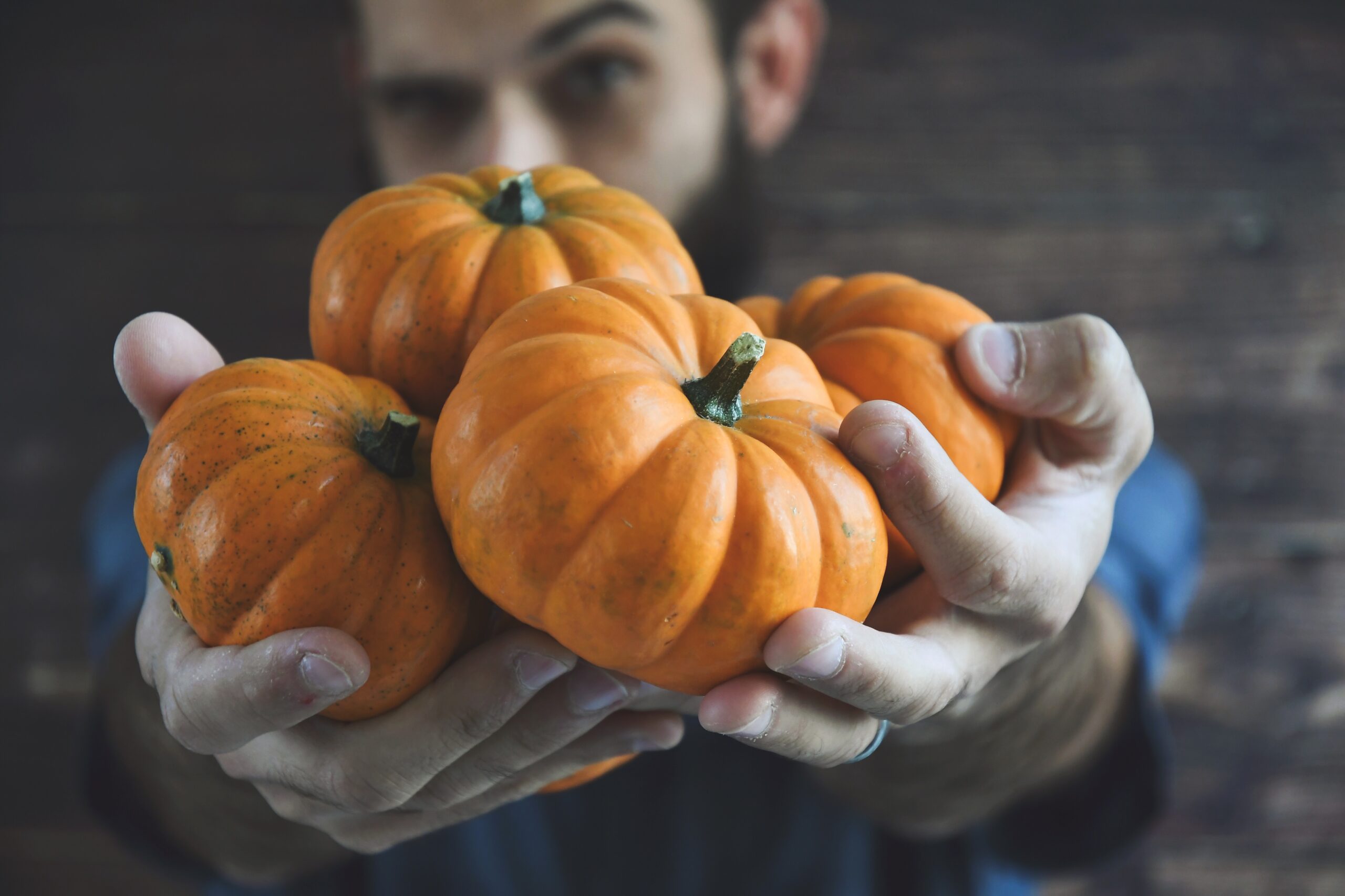 Man holding miniature orange pumpkins for autumn