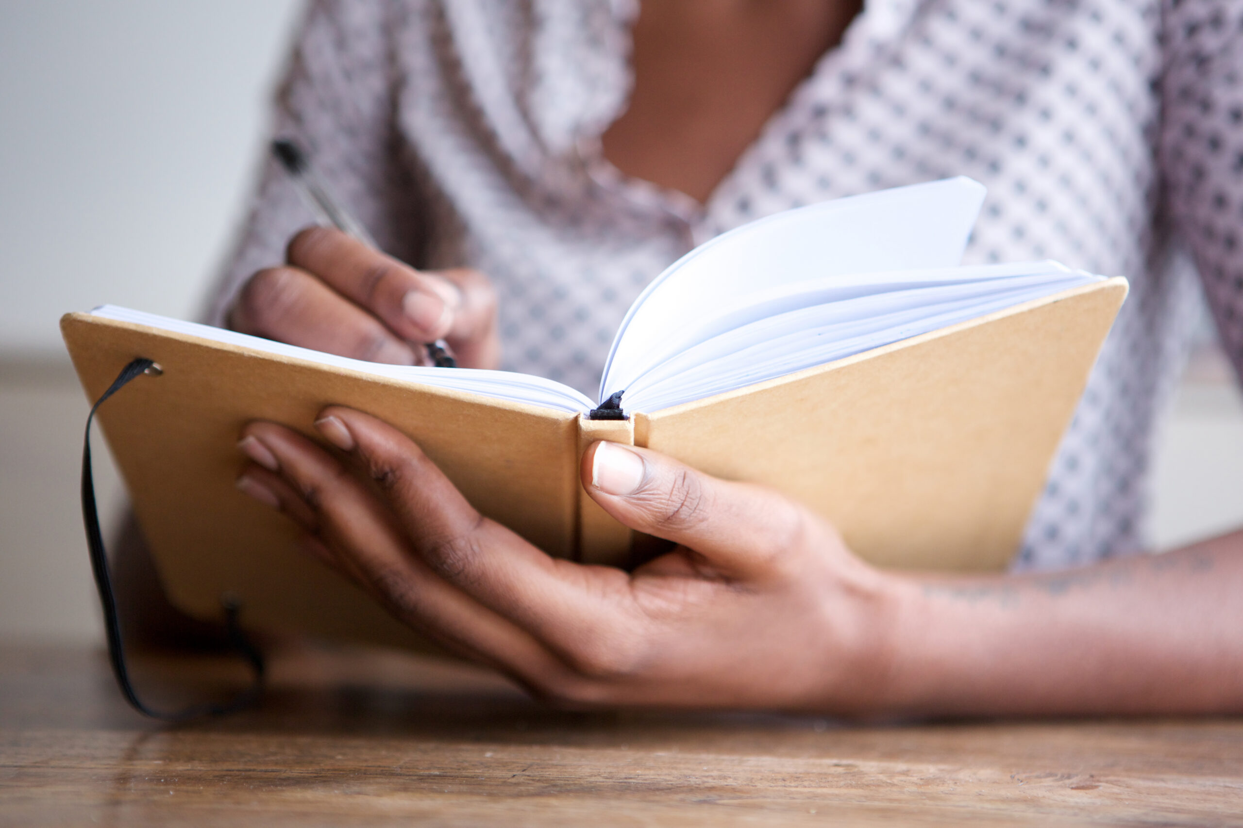 Woman writing in notebook on wooden surface